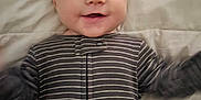 Nolan is registered to the contest to win money with this photo: baby, infant, smile, face, eyes, striped_onesie, onesie, happy, lying_down, bed, sheet, portrait, closeup, head, arms, hands, skin, cute, small_person, infant_clothing