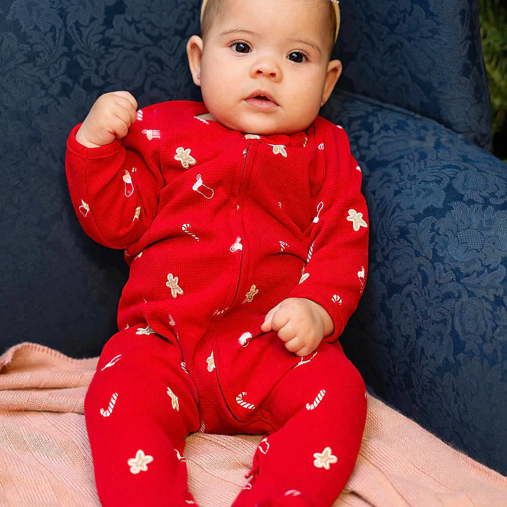 Tayla is registered to the contest to win money with this photo: armchair, baby, blue_fabric, bow, candy_cane_pattern, child, clothing, cute, expression, face, gingerbread_pattern, headband, holiday_theme, indoors, infant, pink_blanket, portrait, red_onesie, sitting, soft_lighting