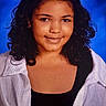 Dakota is registered to the contest to win money with this photo: child, portrait, smiling, curly_hair, dark_hair, face, eyes, headshot, studio, blue_background, white_shirt, black_top, clothing, person, looking_at_camera, front_facing, shoulders, indoor, photography, confident_expression