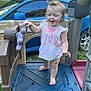 toddler, child, barefoot, playground, toy, steering_wheel, plastic, blue, car, outdoor, grass, greenery, smiling, happy, short_sleeves, dress, daylight, person, young_child, play