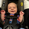 Joshua is registered to the contest to win money with this photo: baby, child, car_seat, smiling, safety_harness, clothing, denim, striped_shirt, infant, seat_belt, padded, cute, happy, hands, head, face, person, indoor, closeup, secured