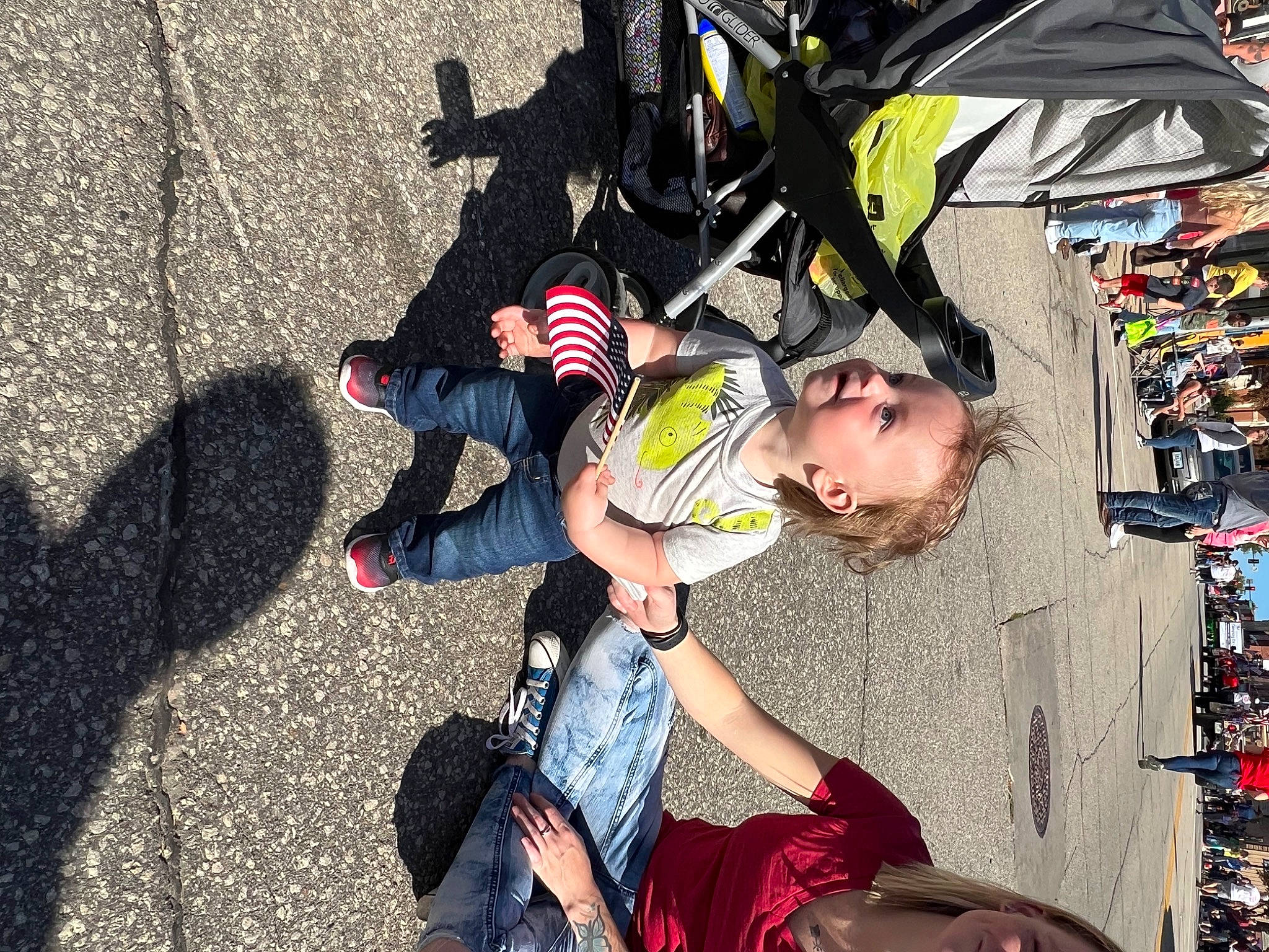 Henry joined the competition — help win amazing prizes! asphalt, bag, boot, child, city, event, fun, human_leg, leisure, luggage_and_bags, pedestrian, person, recreation, road, sandal, shorts, sidewalk, sitting, sneakers, street