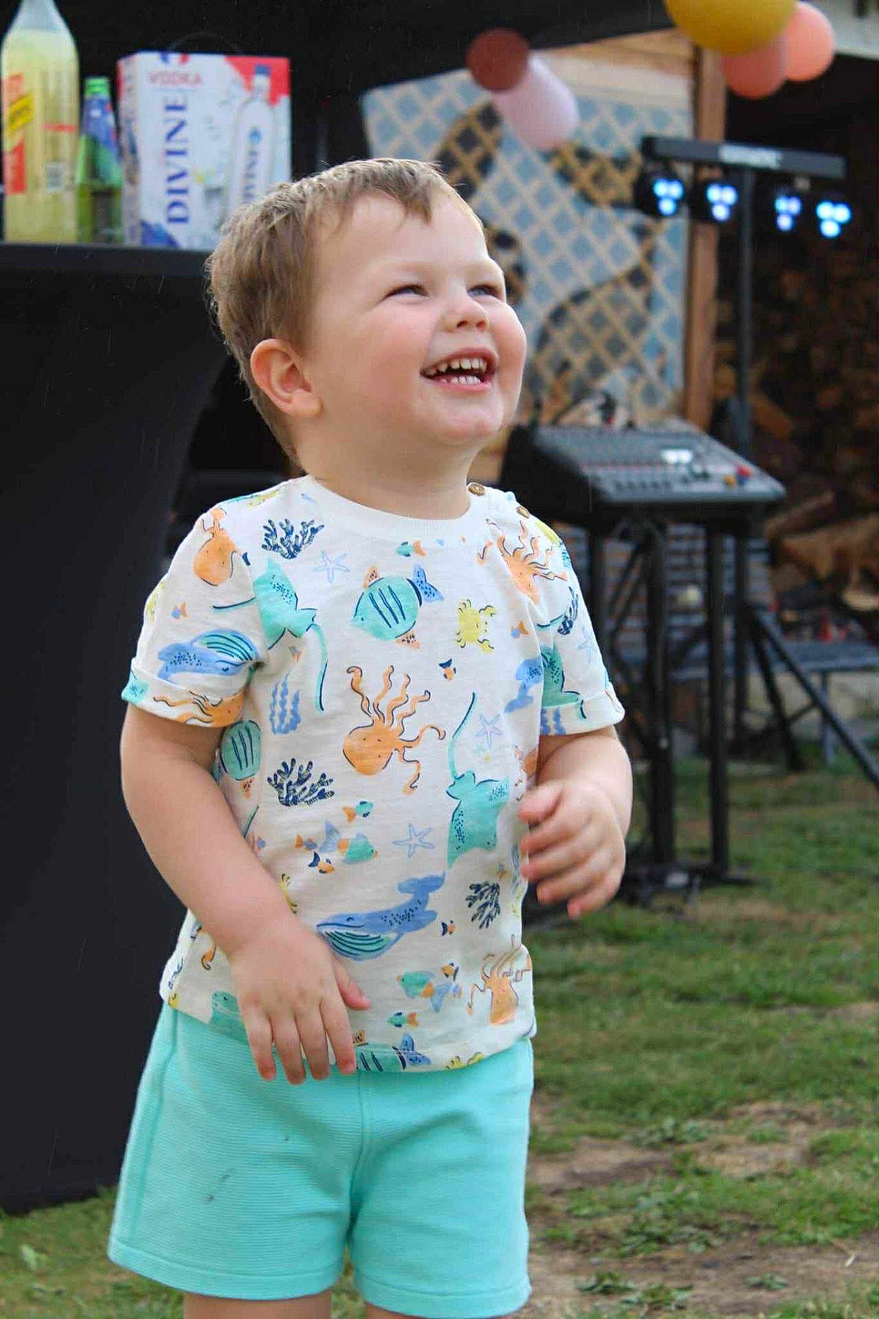 David participe au concours pour gagner de l'argent avec cette photo : child, toddler, smiling, laughing, shorts, shirt, outdoor, grass, party, balloons, sound_equipment, happy, cute, summer, playful, fun, young, casual_clothing, daylight, celebration