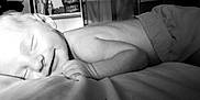 Lyam participe au concours pour gagner de l'argent avec cette photo : baby, sleeping, smiling, infant, bed, pillow, soft, cozy, indoors, peaceful, child, cute, relaxing, monochrome, black_and_white, face, hand, diaper, rest, young