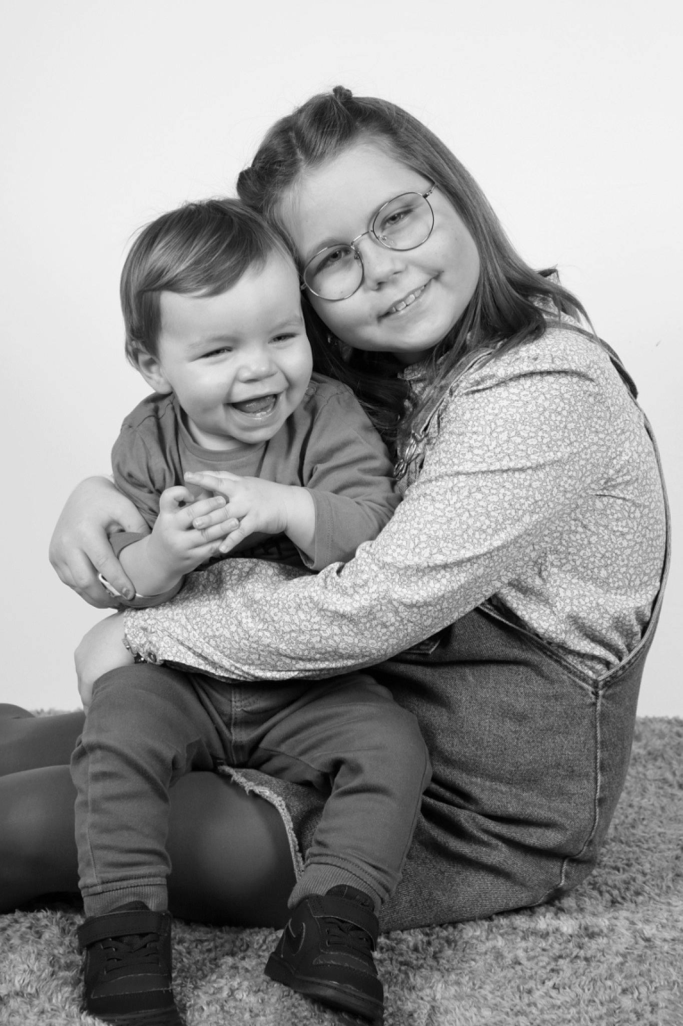 Charlie a rejoint le concours — aidez-le/la à gagner de superbes lots ! black_and_white, child, family, happy, hug, interaction, joy, laugh, monochrome, monochrome_photography, people, person, photograph, photography, portrait, portrait_photography, sibling, sitting, smile, snapshot