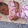 Crystal joined the competition — help win amazing prizes! baby, infant, child, portrait, lying_down, pink_pajamas, sleepwear, blanket, bed, nursery, curly_hair, dark_skin, looking_at_camera, side_eye, cozy, indoor, relaxed, star_pattern, textile, closeup