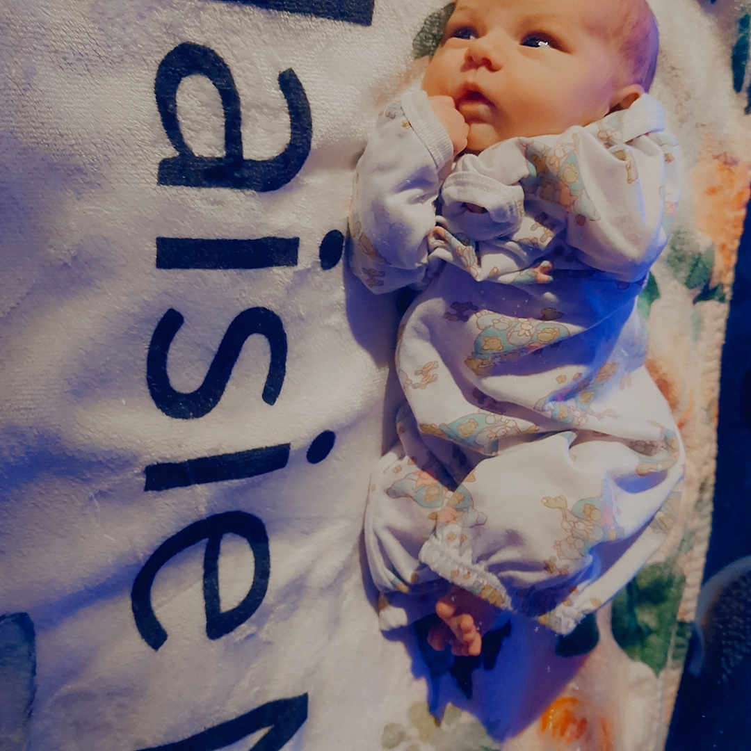 Maisie Mae is registered to the contest to win money with this photo: baby, blanket, child, cute, face, floral, foot, hand, indoor, infant, lying_down, newborn, onesie, patterned_clothing, portrait, resting, skin, sleepwear, soft_texture, text