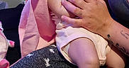 Bella is registered to the contest to win money with this photo: baby, infant, pacifier, headband, pink, sleeping, hands, adult, holding, clothing, legs, feet, tattoo, arm, fabric, couch, relaxation, indoor, person, comfort