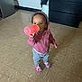 casual_clothing, child, colorful_shoes, cute, daylight, drinking, floor, gray_pants, home, hoodie, indoor, person, pink_cup, pink_hoodie, shoes, socks, standing, tile_floor, toddler, young_child