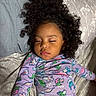 child, sleeping, curly_hair, pajamas, bed, blanket, face, peaceful, indoors, resting, cute, young_child, person, clothing, patterned, comfort, toddler, nap, relaxation, hair
