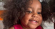 Nayla is registered to the contest to win money with this photo: child, toddler, smile, curly_hair, pink_top, indoor, face, person, happy, cute, portrait, hair_puffs, skin, head, clothing, baby, young_child, expression, people, closeup
