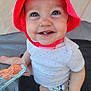 baby, child, smiling, red_hat, blue_eyes, white_onesie, polka_dots, teeth, sitting, tent, indoor, holding_object, bright_colors, happy, cute, skin, infant, toy, closeup, portrait
