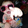 toddler, child, sunglasses, pointing, smiling, pink, colorful, clothing, indoors, padded_rail, joyful, playful, face, hand, person, expression, casual, fun, toy, background