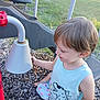 child, boy, playground, outdoor, grass, wood_chips, plastic, dinosaur_shirt, light_hair, sleeveless_shirt, play_equipment, summer, daylight, smiling, curious, casual_clothing, nature, recreation, fun, park