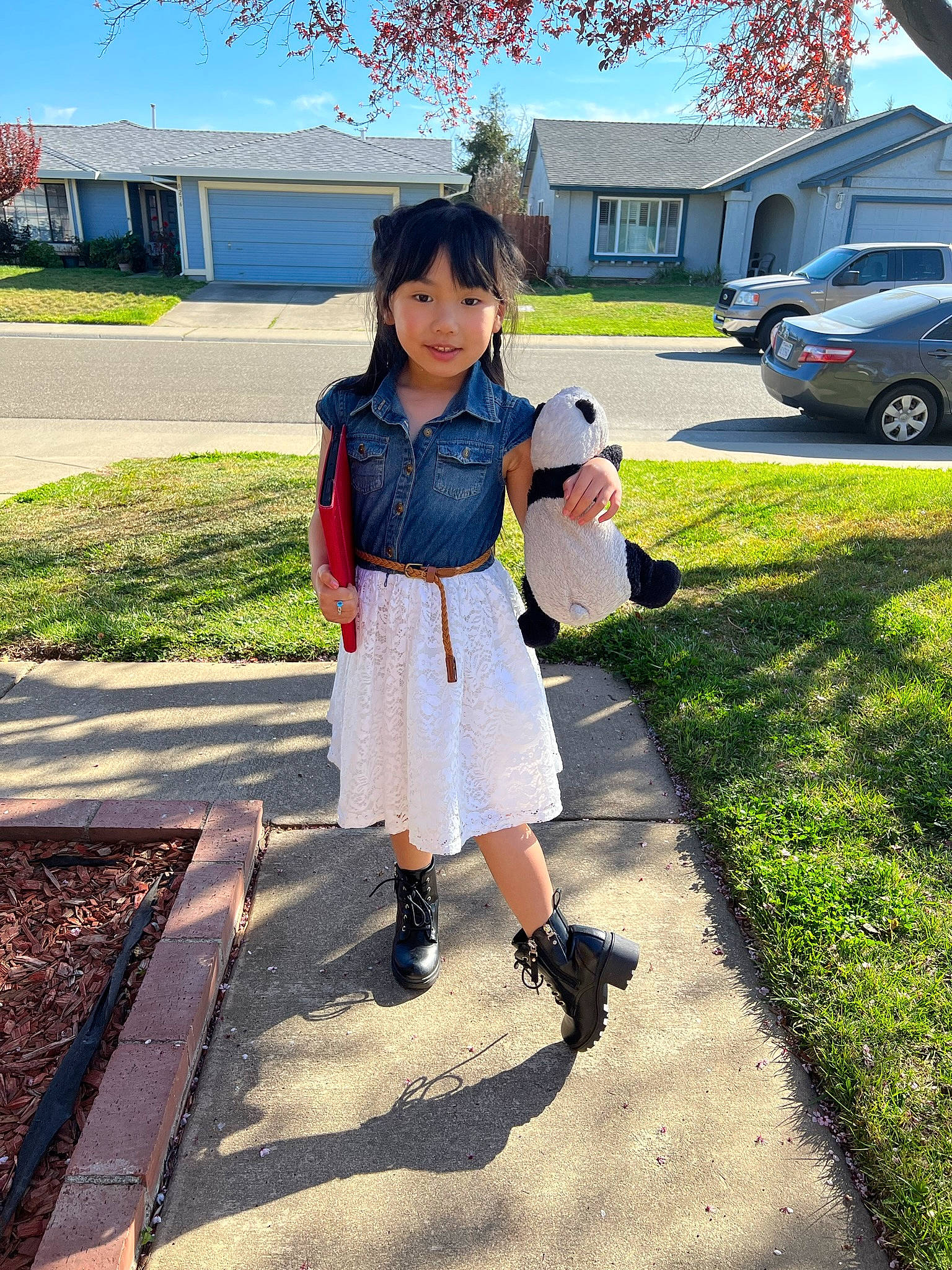Amina is registered to the contest to win money with this photo: asphalt, car, denim, electric_blue, human_leg, knee, leisure, person, plaid, plant, school_uniform, shoe, sidewalk, sky, tartan, tints_and_shades, toddler, tree, trunk, waist