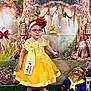 child, girl, toddler, yellow_dress, bow, headband, rose, glasses, butterflies, backdrop, stuffed_animal, plush_toy, pageant, contest_number, red_shoes, grass, fairy_tale, portrait, indoor, costume