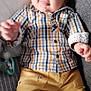 baby, child, clothing, couch, cozy, cute, face, hand, happy, head, home, indoor, infant, person, pillow, plaid_shirt, relaxing, sitting, smiling, yellow_pants