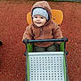 Livio a rejoint le concours — aidez-le/la à gagner de superbes lots ! baby, child, cold_weather, cute, fence, happy, hat, jacket, outdoor, person, play, playground, red_surface, rocker, seat, smile, smiling, toddler, toy, winter_clothing