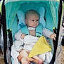 Livio a rejoint le concours — aidez-le/la à gagner de superbes lots ! baby, blanket, blue, child, clothing, curious, cute, footwear, head_support, infant, outside, pavement, person, plastic_cover, rain_cover, seatbelt, small, stroller, wet, yellow