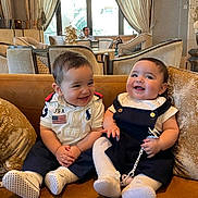 Lilia a rejoint le concours — aidez-le/la à gagner de superbes lots ! baby, blue_clothing, child, couch, curtains, cute, decor, furniture, happy, indoor, infant, laughing, pacifier, person, sitting, smiling, sock, soft_toys, white_clothing, window