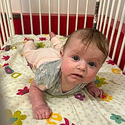 Brooklyn joined the competition — help win amazing prizes! baby, bedding, child, clothing, colorful, crib, cute, eyes, face, fingers, flower_pattern, gray_shirt, hand, indoors, infant, letters, pink_pants, red_background, tummy_time, wooden_bars