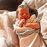 newborn, baby, infant, smile, blanket, swaddle, hand, person, soft_light, cozy, sleeping, cute, rest, comfort, warmth, indoor, fabric, skin, closeup, portrait