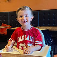 Jessy a rejoint le concours — aidez-le/la à gagner de superbes lots ! boy, casual_clothing, child, cute, face, furniture, haircut, happy, high_chair, indoor, kid, oakland, pacifier, person, red_shirt, restaurant, seat, smiling, table, wooden_spoon