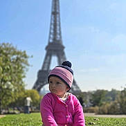 Lynda-Rose participe au concours pour gagner de l'argent avec cette photo : toddler, child, grass, hat, pink_sweater, shoes, outdoor, daylight, eiffel_tower, landmark, sky, trees, park, sitting, portrait, person, nature, casual_clothing, cute, urban