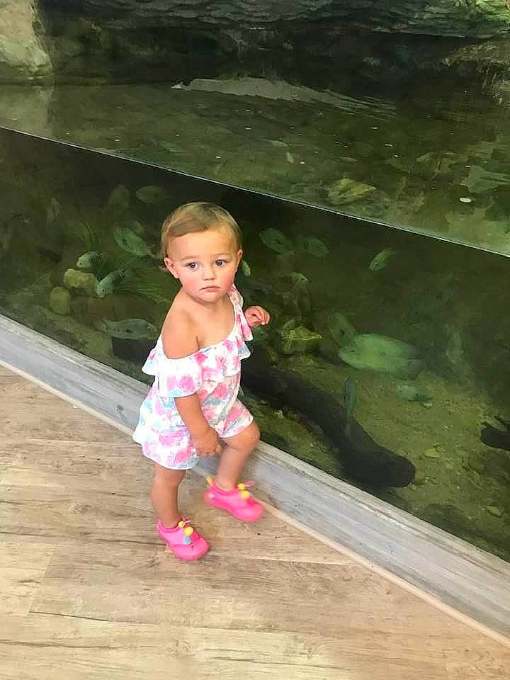 Senua is registered to the contest to win money with this photo: baby_toddler_clothing, body_of_water, child, flooring, foot, fun, grass, happy, hardwood, human_leg, leisure, person, plant, sandal, shorts, sitting, toddler, tree, vertebrate, water