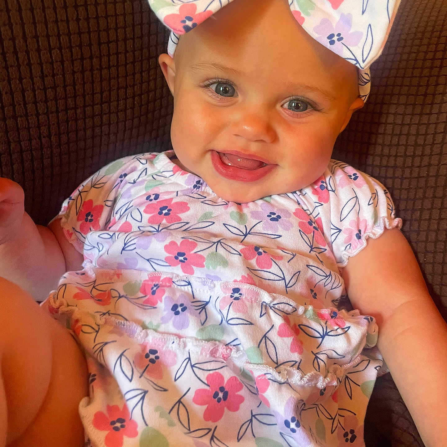 Meg joined the competition — help win amazing prizes! baby, background, bow, bright_eyes, child, clothing, cute, expression, face, floral_outfit, happy, headband, indoors, infant, pattern, person, sitting, skin, smile, texture