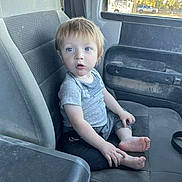 Brayden joined the competition — help win amazing prizes! toddler, child, car_seat, barefoot, gray_clothing, blue_eyes, curious, indoor, vehicle_interior, window, plastic_bag, paper, seat, dusty, young_child, person, sitting, expression, casual, portrait