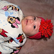 Aïvy a rejoint le concours — aidez-le/la à gagner de superbes lots ! baby, infant, child, headband, flower_headband, red_flower, onesie, minnie_mouse, cartoon_print, bow, face, eyes, cheeks, nose, blanket, soft_texture, pink, red, portrait, close_up