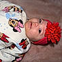 baby, infant, child, headband, flower_headband, red_flower, onesie, minnie_mouse, cartoon_print, bow, face, eyes, cheeks, nose, blanket, soft_texture, pink, red, portrait, close_up