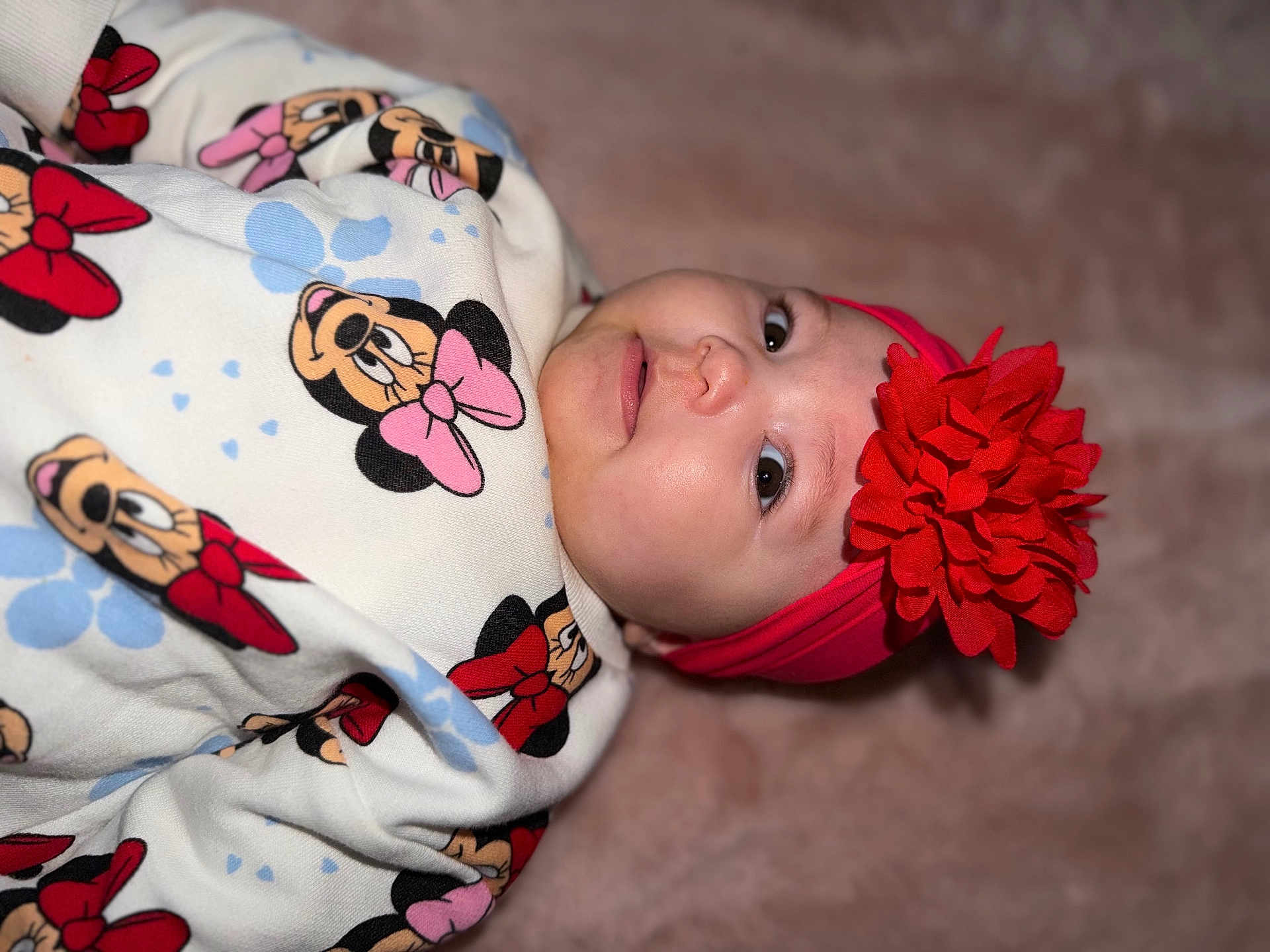 Aïvy a rejoint le concours — aidez-le/la à gagner de superbes lots ! baby, infant, child, headband, flower_headband, red_flower, onesie, minnie_mouse, cartoon_print, bow, face, eyes, cheeks, nose, blanket, soft_texture, pink, red, portrait, close_up