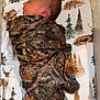newborn, baby, sleeping, blanket, camouflage, crib, bedding, forest, deer, pine_trees, infant, resting, child, cozy, pattern, animal_print, peaceful, indoor, cute, portrait