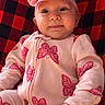 baby, infant, child, onesie, pink, butterfly_pattern, headband, bow, red_and_black_blanket, blanket, cute, smiling, portrait, indoors, soft_texture, clothing, hand, face, happy, baby_girl