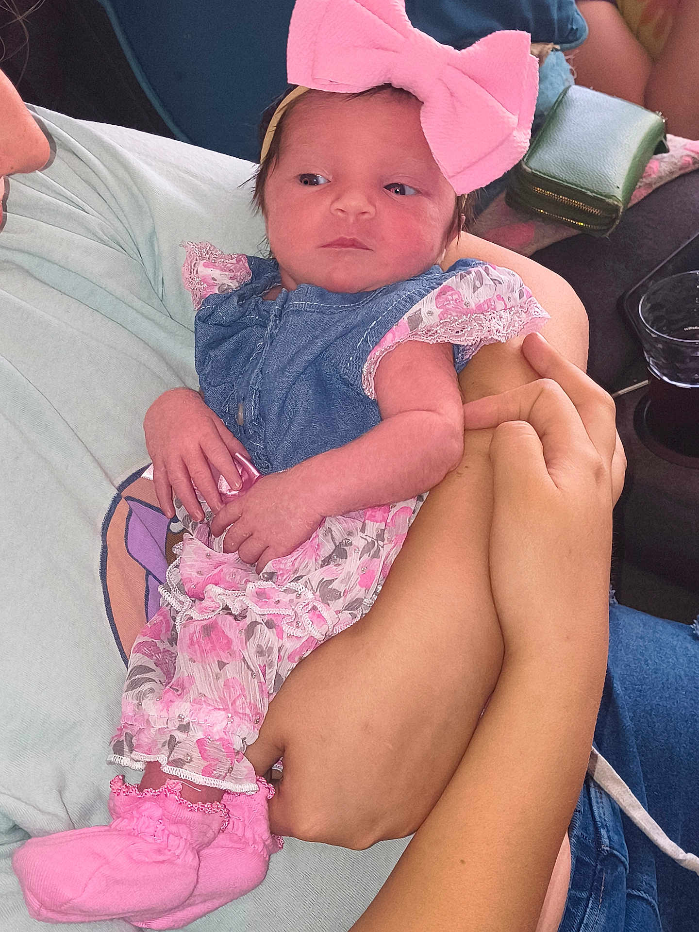 Paris is registered to the contest to win money with this photo: baby, infant, child, pink_bow, denim, dress, socks, hands, arms, person, clothing, cute, portrait, indoor, fabric, holding, newborn, soft, cozy, human