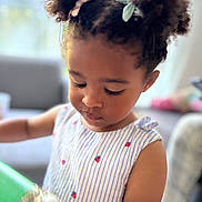 Enaya participe au concours pour gagner de l'argent avec cette photo : candid, child, closeup, curly_hair, cute, dress, focused, girl, hairstyle, holding, home, indoor, person, pigtails, playing, portrait, soft_light, striped_clothing, toddler, young_child