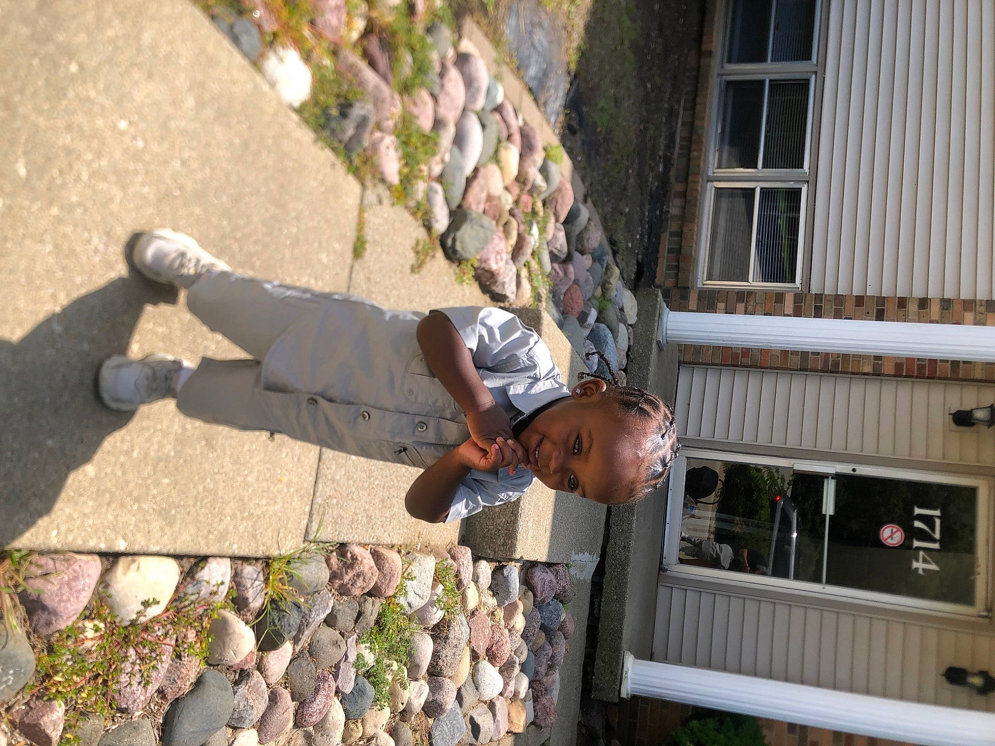 Dash is registered to the contest to win money with this photo: adventure, child, cobblestone, concrete, facade, grass, hand, human_leg, leisure, person, plant, recreation, road_surface, rock, shadow, sidewalk, t_shirt, toddler, window, wood