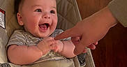 Carmine is registered to the contest to win money with this photo: baby, babybjorn, child, clothing, cute, face, finger, furniture, hand, happy, indoor, infant, joy, person, seat, skin, smile, socks, striped_pants, wooden_floor