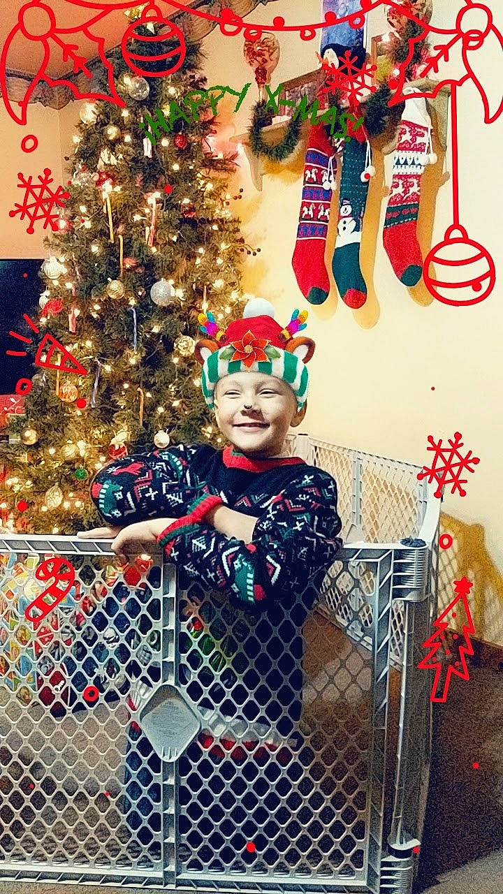Jaydon joined the competition — help win amazing prizes! christmas_decoration, christmas_ornament, christmas_tree, conifer, entertainment, event, fence, fun, happy, headwear, holiday, holiday_ornament, joy, mesh, ornament, party_supply, pattern, person, red, toddler
