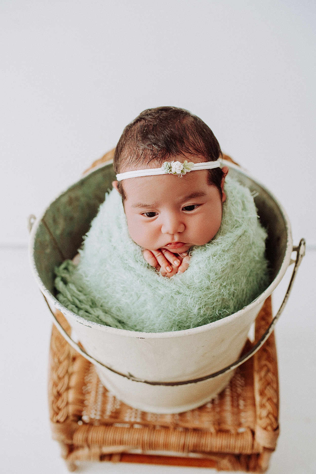 Sara joined the competition — help win amazing prizes! baby, infant, bucket, blanket, headband, wicker, stool, wrapped, cute, portrait, soft_texture, white_background, hands, face, newborn, resting, indoors, decorative, peaceful, adorable