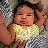 baby, infant, child, face, hand, clothing, striped_dress, yellow, blue, bed, pillow, blanket, cute, chubby_cheeks, portrait, indoor, person, skin, fingers, lying_down