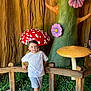 child, boy, white_shirt, gray_shorts, sneakers, mushrooms, purple_flowers, tree, wooden_fence, greenery, indoor, decorative, playful, casual_pose, smiling, background, fantasy, colorful, young, portrait
