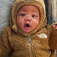 Alijah joined the competition — help win amazing prizes! baby, brown_clothing, casual_wear, child, couch, cozy, cute, face, fuzzy_jacket, hood_with_ears, indoor, infant, person, portrait, soft_texture, surprised_expression, warm_clothing, wide_eyes, young_child, zipper