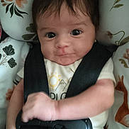 éden is registered to the contest to win money with this photo: baby, infant, car_seat, safety_harness, floral_pattern, clothing, cute, face, expression, child, seat, strapped_in, adorable, young, person, indoor, portrait, holding, hands, smile