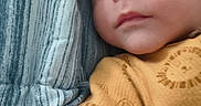 éden is registered to the contest to win money with this photo: baby, child, infant, face, portrait, onesie, yellow_clothing, lying_down, blue_blanket, striped_blanket, expression, curious, skin, arm, head, young_child, indoors, closeup, person, sleepwear