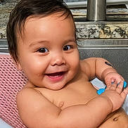 Mariana is registered to the contest to win money with this photo: baby, smiling, sink, bath, water_droplets, toy, happy, child, kitchen, pink_bath_mat, face, skin, arm, hand, faucet, countertop, liquid_wash_bottle, indoor, person, cute