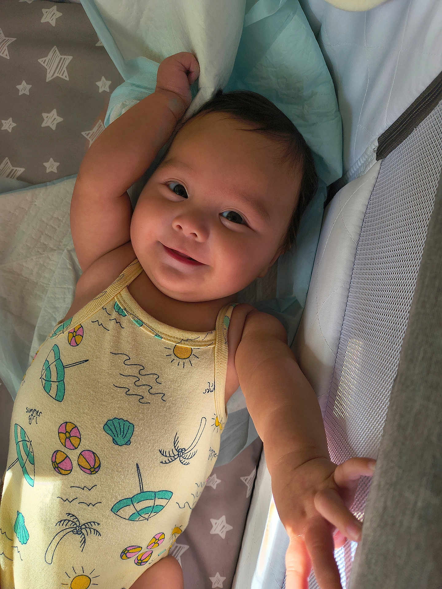 Mariana is registered to the contest to win money with this photo: baby, smiling, infant, onesie, arm, face, bed, bedding, crib, mesh, light, happy, child, person, cute, sleeping_area, toddler, soft, indoors, skin