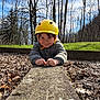 Pablo a rejoint le concours — aidez-le/la à gagner de superbes lots ! child, person, yellow_helmet, helmet, smile, happy, outdoor, forest, trees, leaf_litter, concrete, jacket, hands, grass, sky, clouds, portrait, nature, playtime, daylight